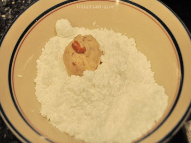 Each of the snowball cookies is rolled in powdered sugar after baking.