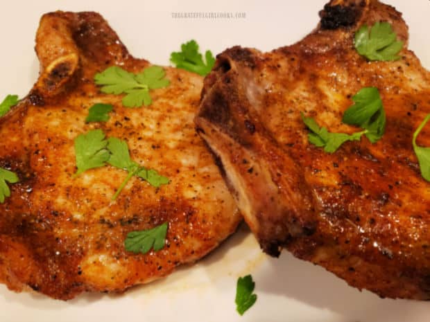 The air fryer pork chops for two are served, garnished with fresh parsley.
