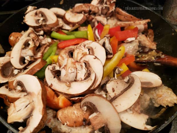 Sliced mushrooms, red, yellow and green bell peppers are added to the skillet.