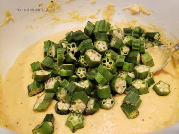 Two cups of sliced okra is added to the cornmeal batter in a large bowl.