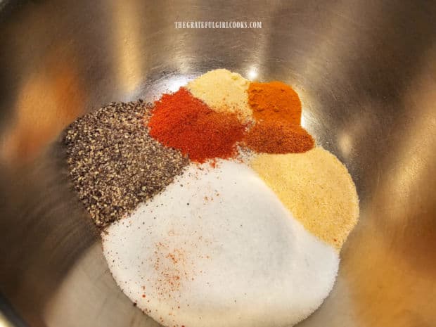 Spices are measured into a small bowl before combining.