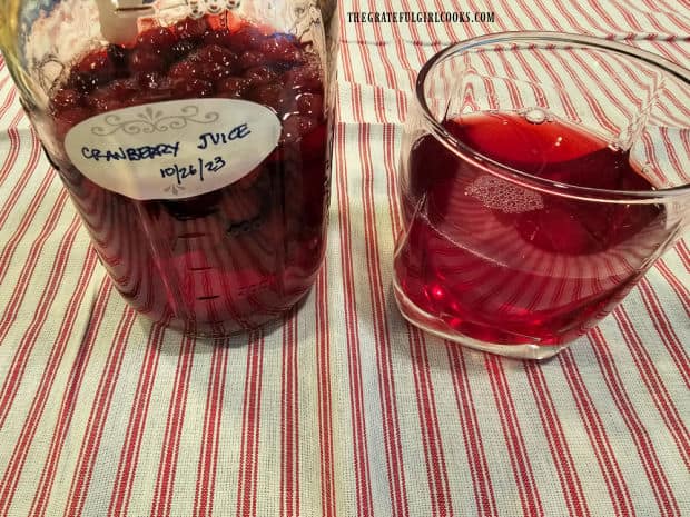 A glass of the homemade cranberry juice with remaining jar on the side.