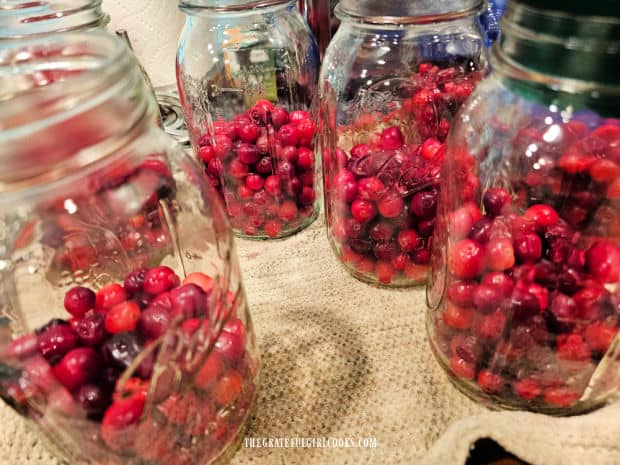 Canning jars with the required amount of cranberries inside.