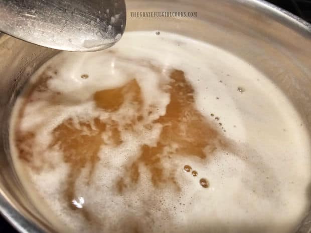 Vegetable broth simmering on a stove while cooking risotto.