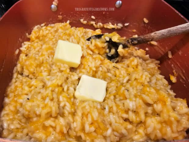 Butter is added to hot pumpkin risotto and stirred until melted.