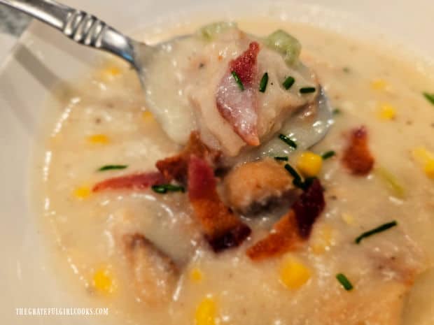 A spoonful of hot rockfish potato chowder, with bacon and chive garnish.