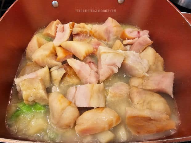 Two-inch pieces of rockfish are placed on top of cooked potatoes in pan.