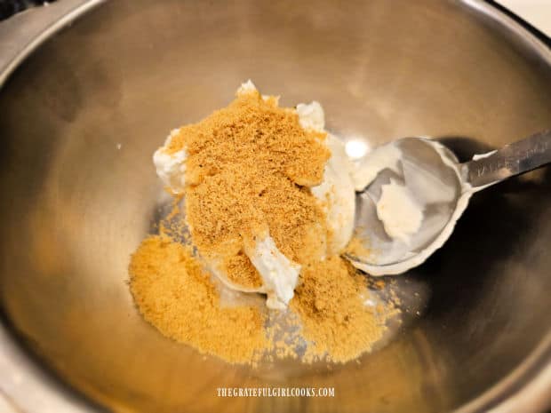 Sour cream and chicken bouillon powder are combined in a small metal bowl.