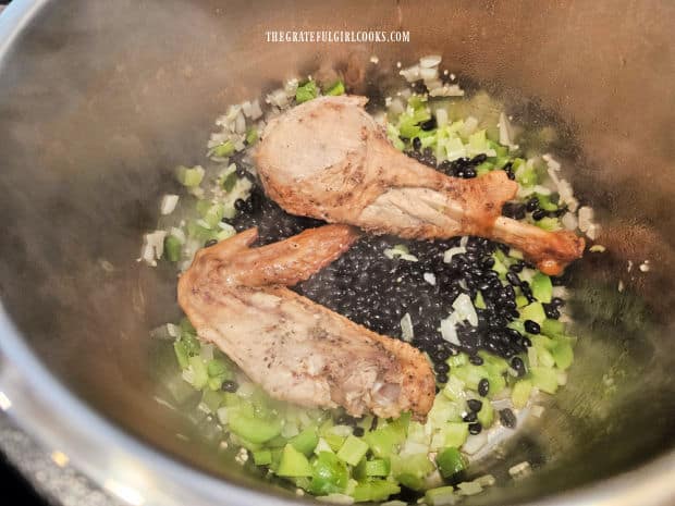 A cooked turkey leg, wing and dried black beans are added to the pot.