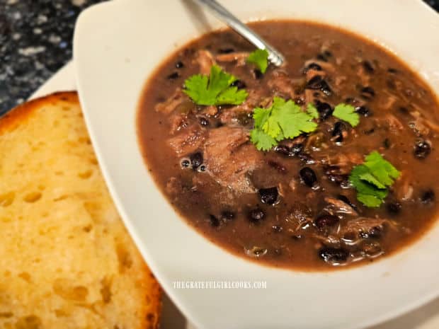 Turkey black bean soup, topped with cilantro, served with bread on the side.