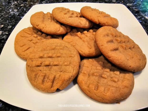 A white plate filled with peanut butter cookies that are ready to be eaten.
