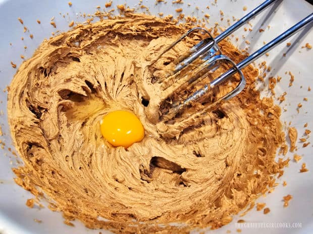 After mixing dough, an egg is beaten into the mixture in the bowl.