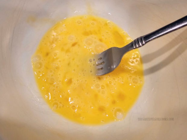 Two eggs are beaten well until fluffy in a large bowl.