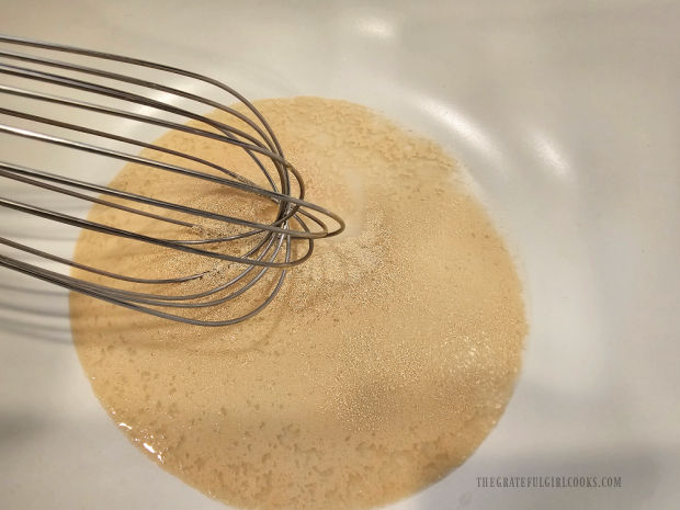 Water, sugar and yeast are whisked to combine in a bowl.