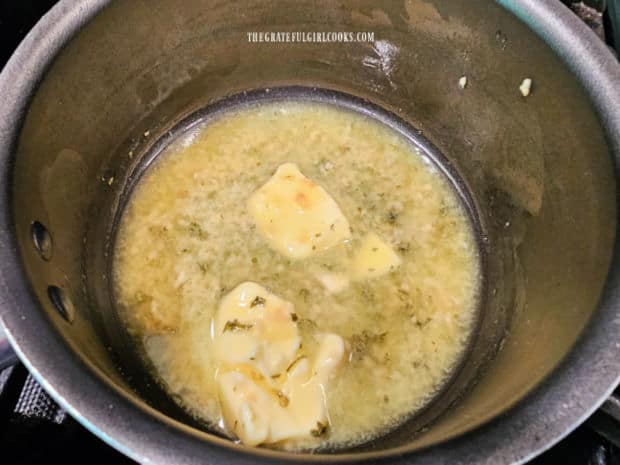 Melted butter, minced garlic and parsley are combined in a saucepan.