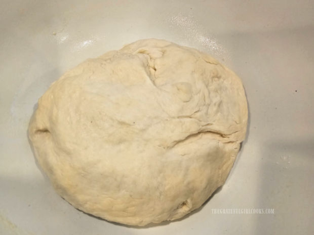 Dough for garlic butter naan bread rises in a large, oiled bowl.