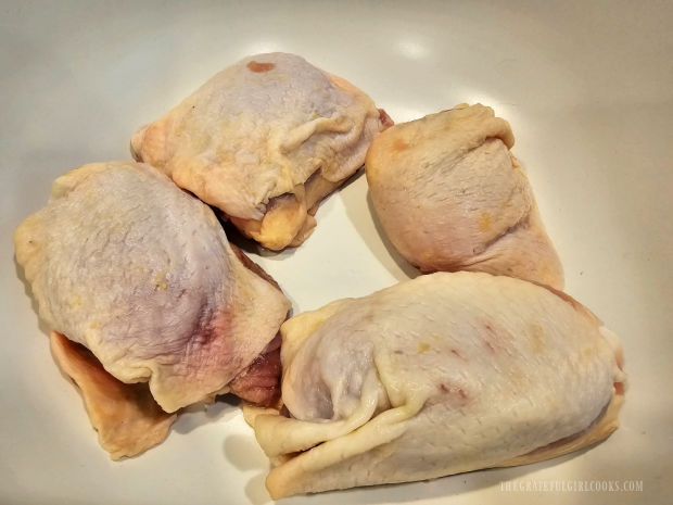 Four bone-in, skin on chicken thighs, ready to be marinated.
