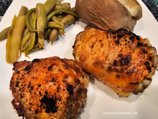 Two garlic herb chicken thighs, served with green beans and baked potato.