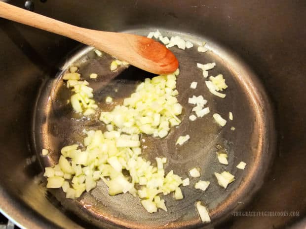 Diced onions are cooked in oil in a large soup pot.