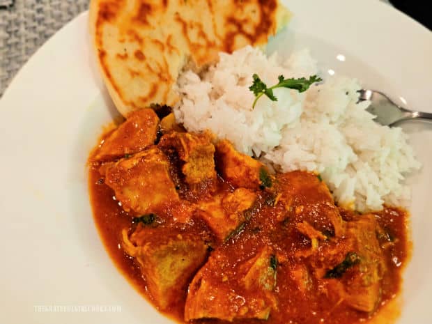 A bowl of butter chicken (Instant Pot), with rice and Naan bread on the side.