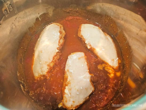 Lid of Instant Pot is unlocked to reveal the cooked chicken breasts.