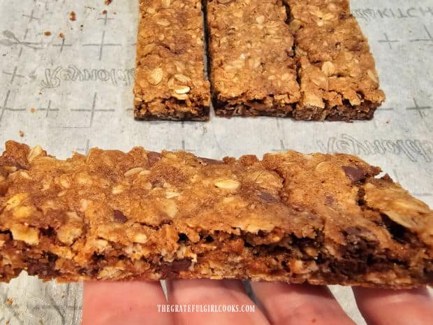 A hand holding a chocolate chip granola bar, with 3 in the background.