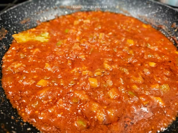 Creole sauce simmers in a large skillet until it has thickened.