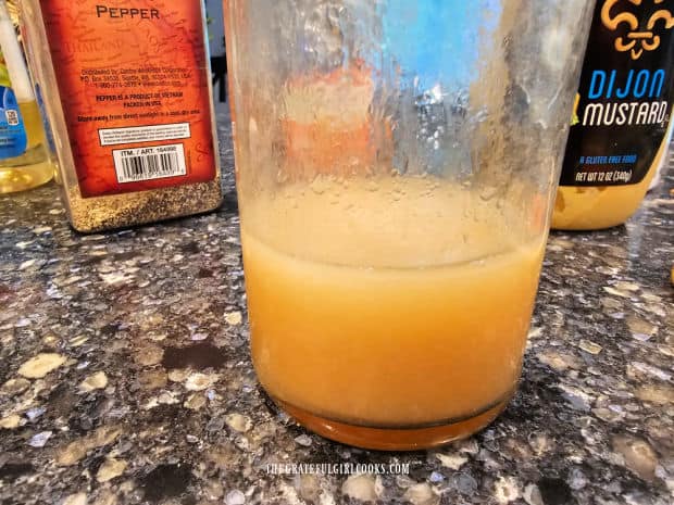 Vegetable oil and apple cider vinegar are combined in jar shown on countertop.