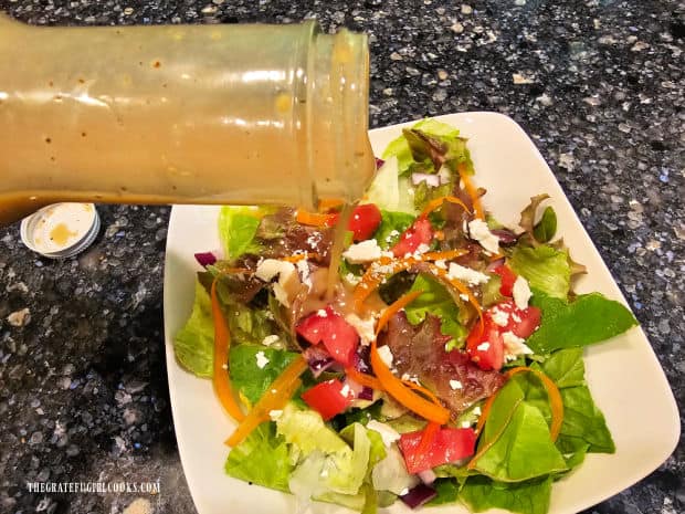 Honey mustard salad dressing is poured over a mixed green salad.