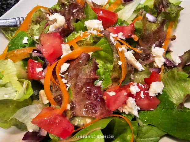 A green salad drizzled with honey mustard salad dressing, ready to eat!