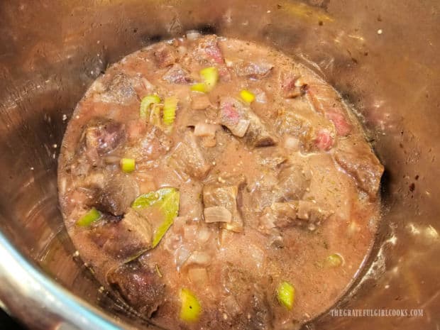 Seasoned beef stew meat is added to the pot and stirred until combined.