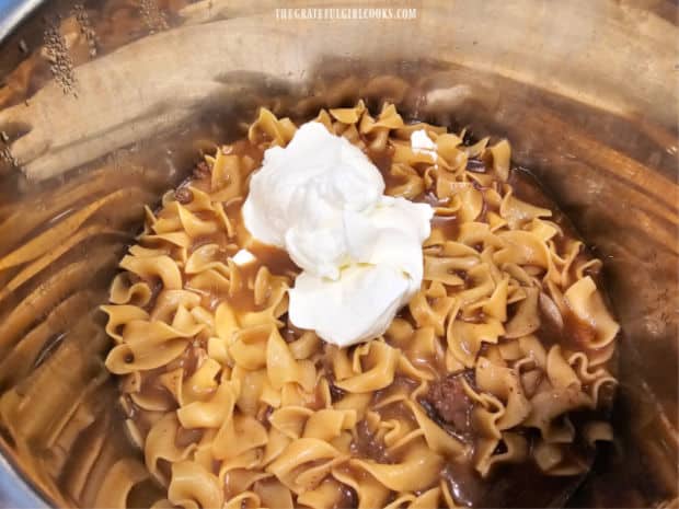 After releasing steam, sour cream is stirred into the stroganoff until combined.