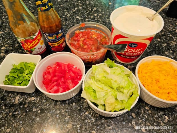 Toppings for refried bean tostadas are placed on counter in small bowls.