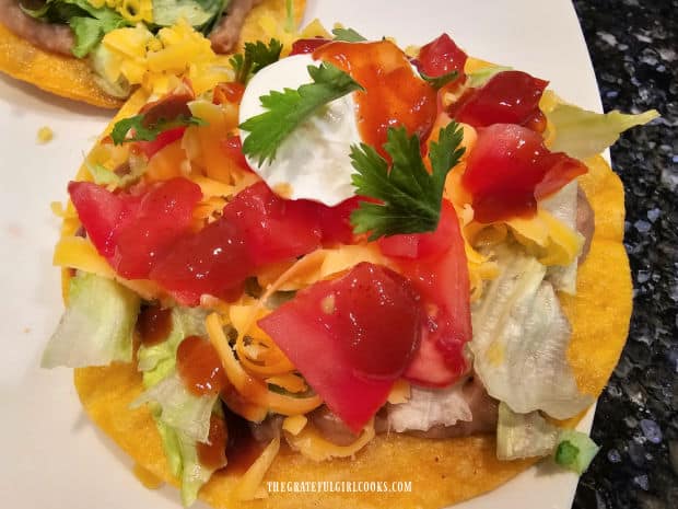 Taco sauce, sour cream and cilantro garnish the top of the tostada.