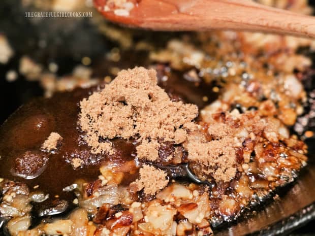 Crispy bacon, brown sugar, maple syrup, etc. are added to onions in skillet.