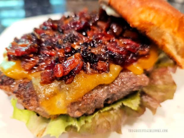 Bacon jam is spread on a grilled cheeseburger on a hamburger bun.