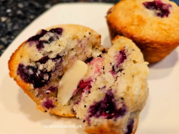 A blueberry lemon poppyseed muffin, sliced open and spread with butter.