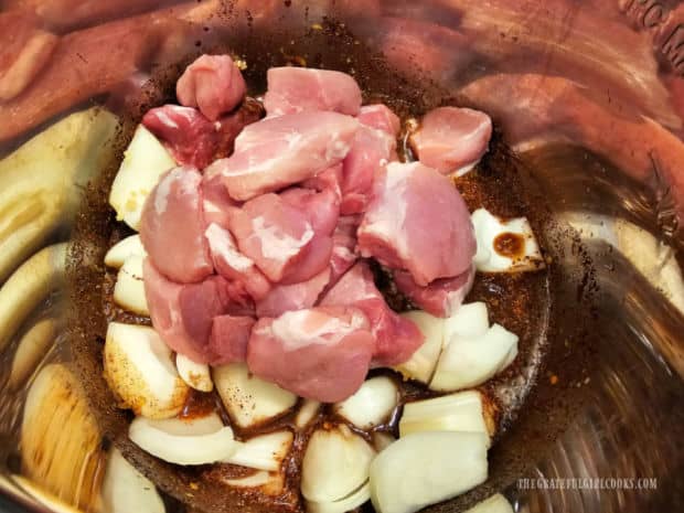 Cubes of pork roast are added to the spices and onions in the pot.