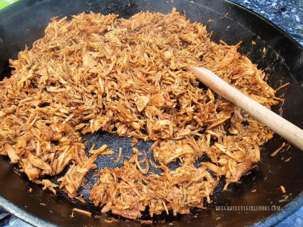 Shredded pork carnitas are reheated in skillet.