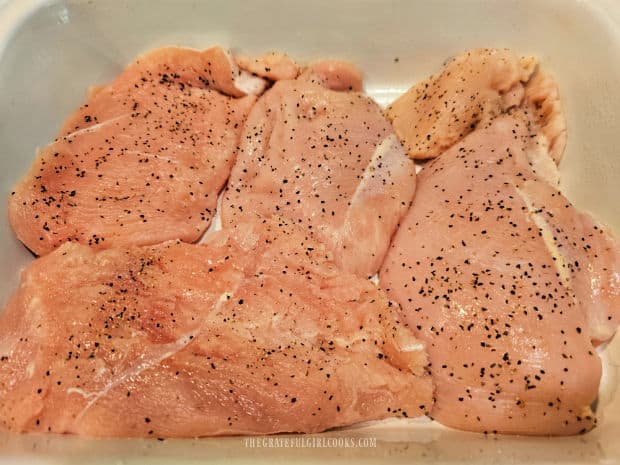 Seasoned chicken breasts in a single layer in greased baking dish.