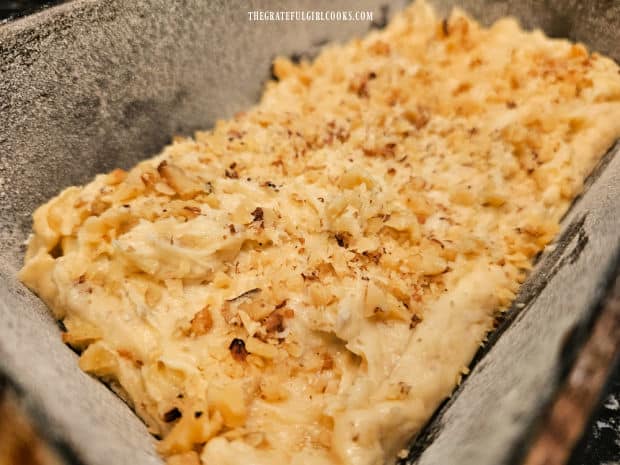 Chopped walnuts are sprinkled on top of the bread loaf before baking.