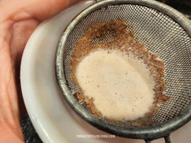 Creamer is strained through a wire mesh strainer to remove used spices.