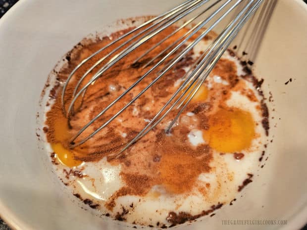 Eggs, milk, sugar, vanilla and cinnamon are whisked together in bowl.