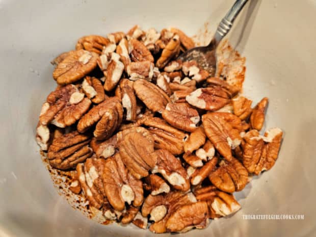 Three cups of unsalted pecan halves are added to the bowl of seasoning mix.