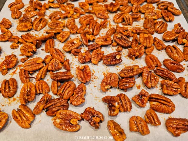 Chili lime roasted pecans cook on parchment paper-lined baking sheet.