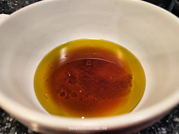 Red wine vinegar and olive oil are poured into a medium bowl.