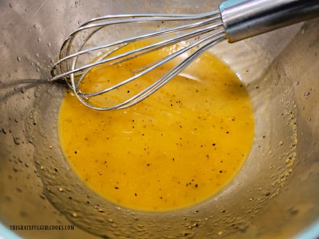 A whisk is used to blend the lemon sauce ingredients in a bowl.