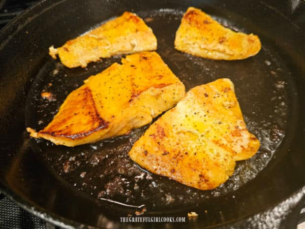 Salmon pieces are flipped, brushed with sauce, then cooked until done.