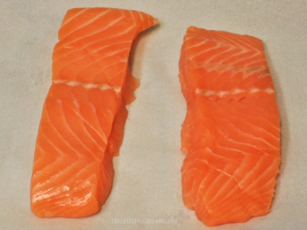 Boneless, skinless salmon fillets are blotted dry using paper towels.