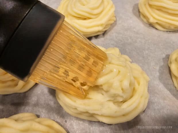 Potatoes are brushed with melted butter before baking.